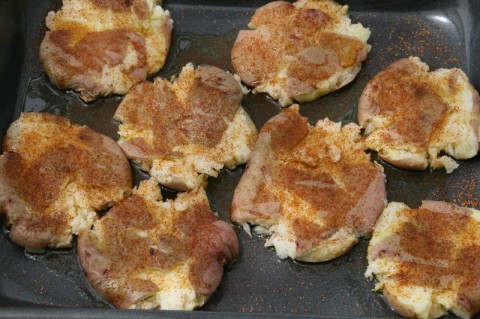 Smashed Potatoes with seasoning on top on a baking pan