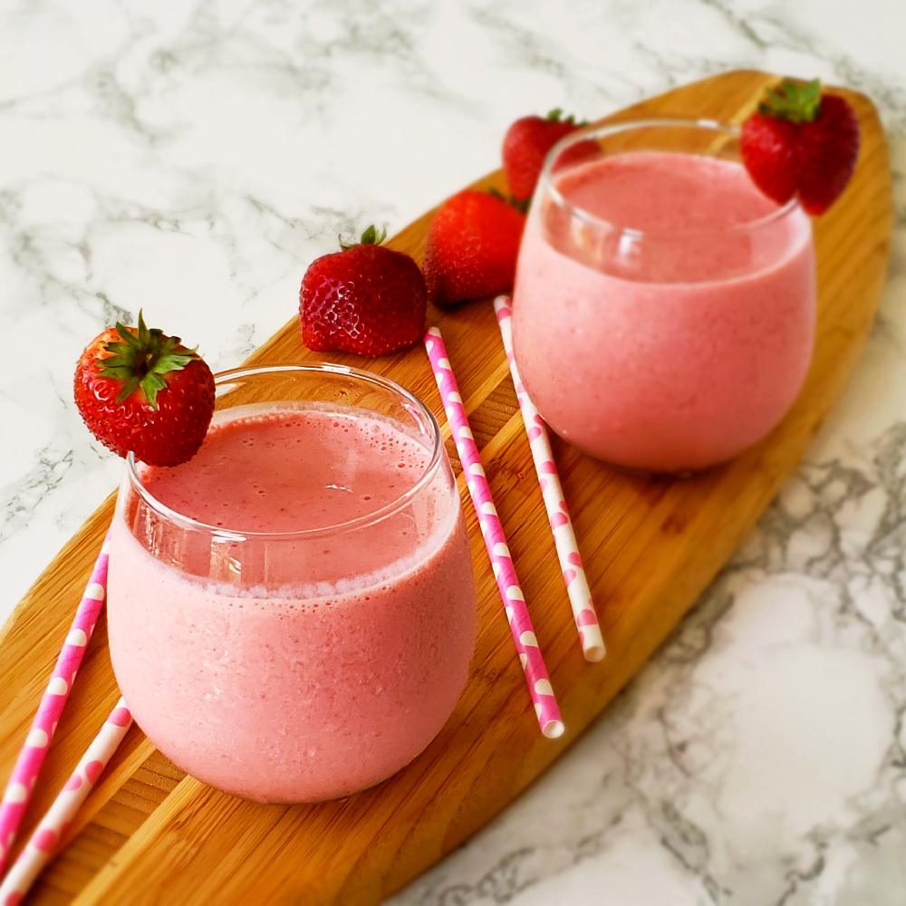 Strawberry Lassi Yogurt beverage in 2 glasses on a wooden board on ShockinglyDelicious.com