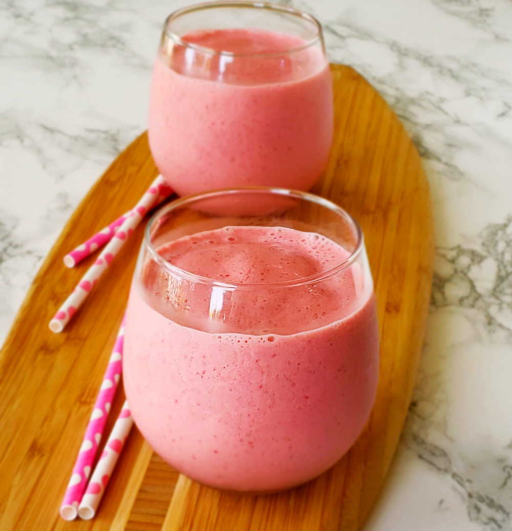 Pink Strawberry Lassi yogurt drink with straws alongside on ShockinglyDelicious.com