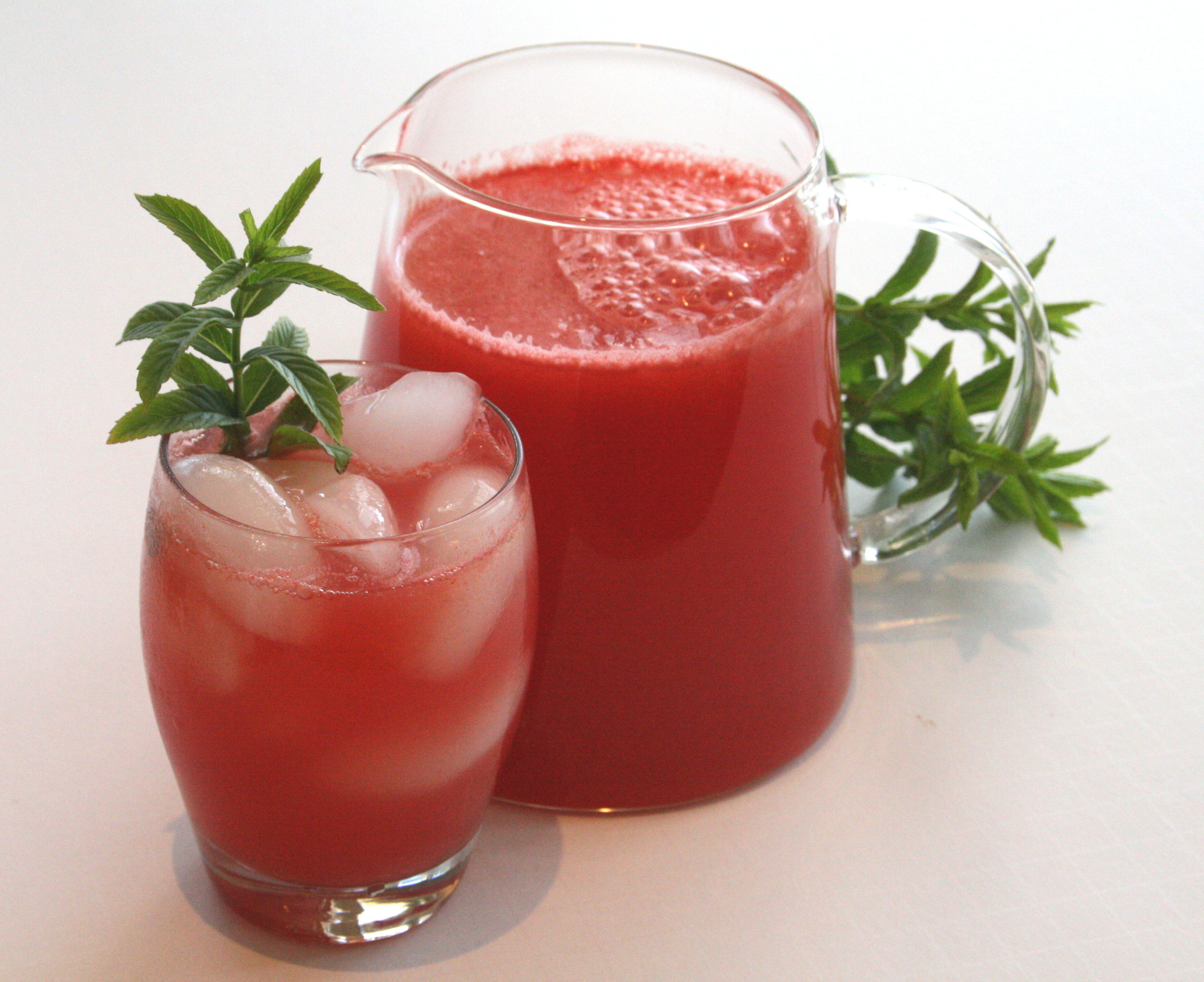 Aqua Fresca Lemonade in a pitcher and a glass with ice cubes against a white background