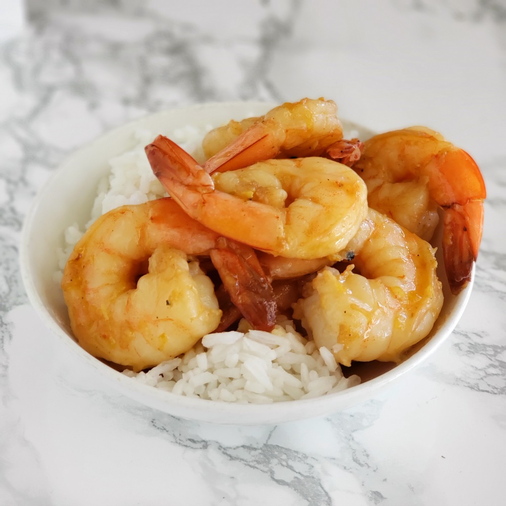 Weeknight Skillet Shrimp on white rice in a white bowl sitting on a white marble counter