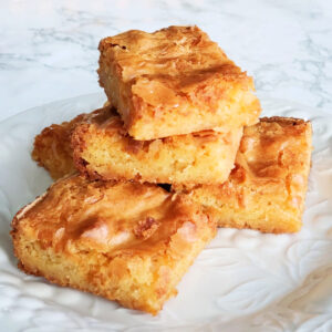 5 White Chocolate Blondies stacked on a white plate on a white marble counter