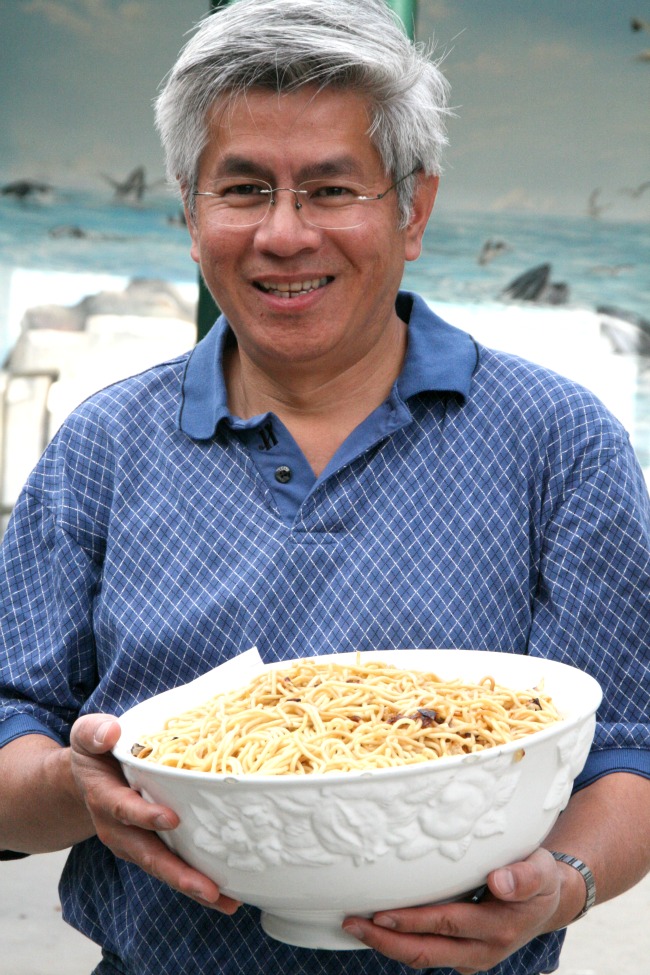 Hung Le holding a white bowl of his famous fried spaghetti