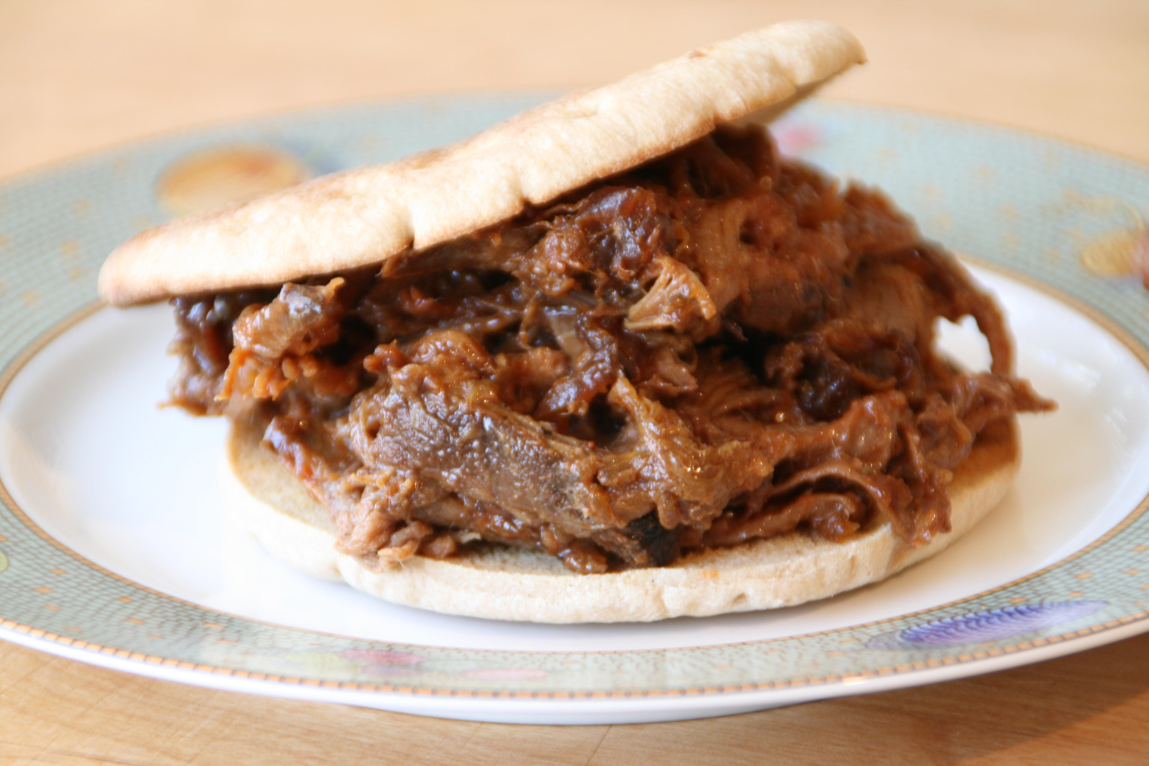 Shredded Beef Brisket stuffed between a sliced slim bun on a small plate