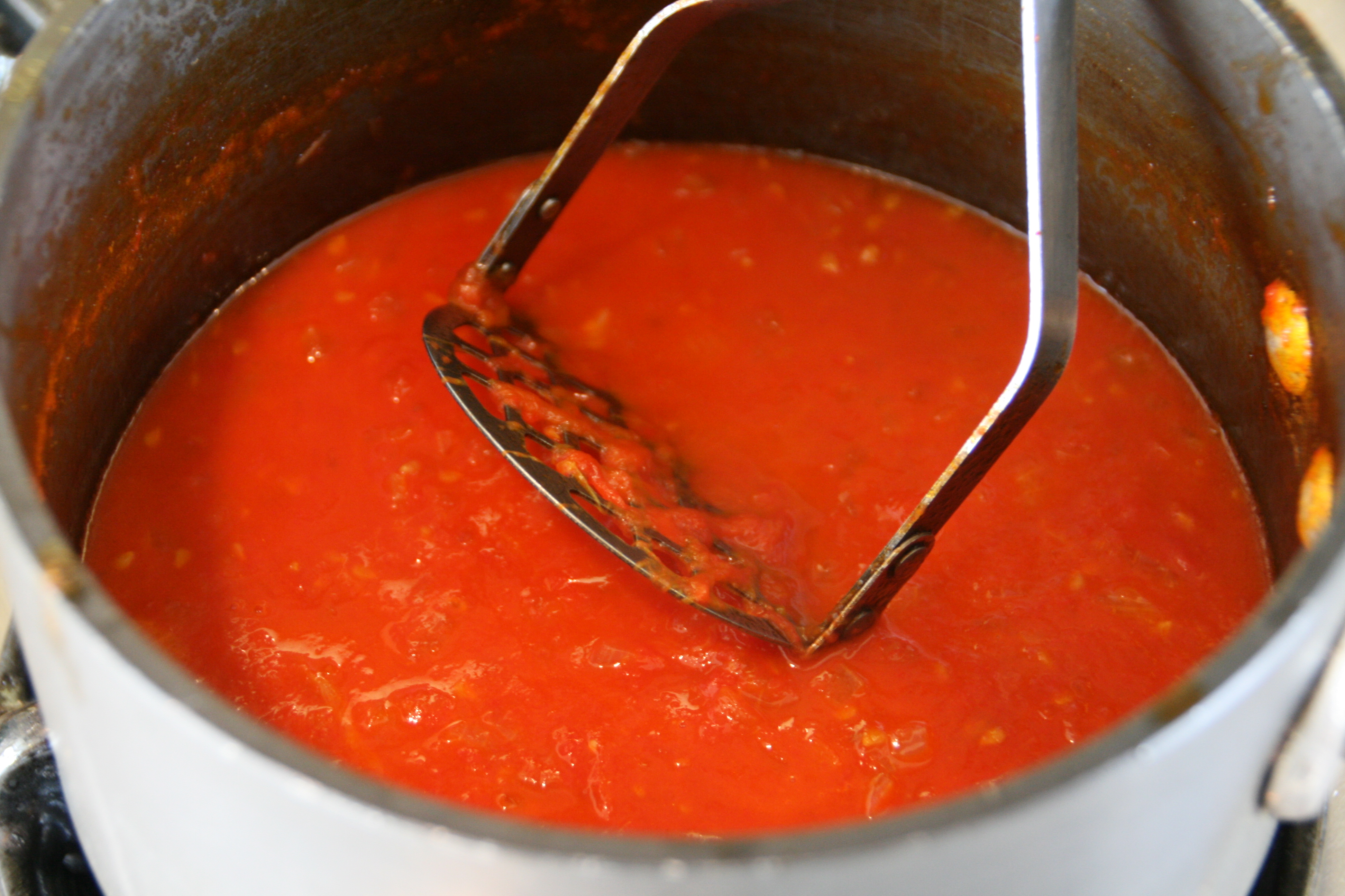 Mash tomatoes with potato masher