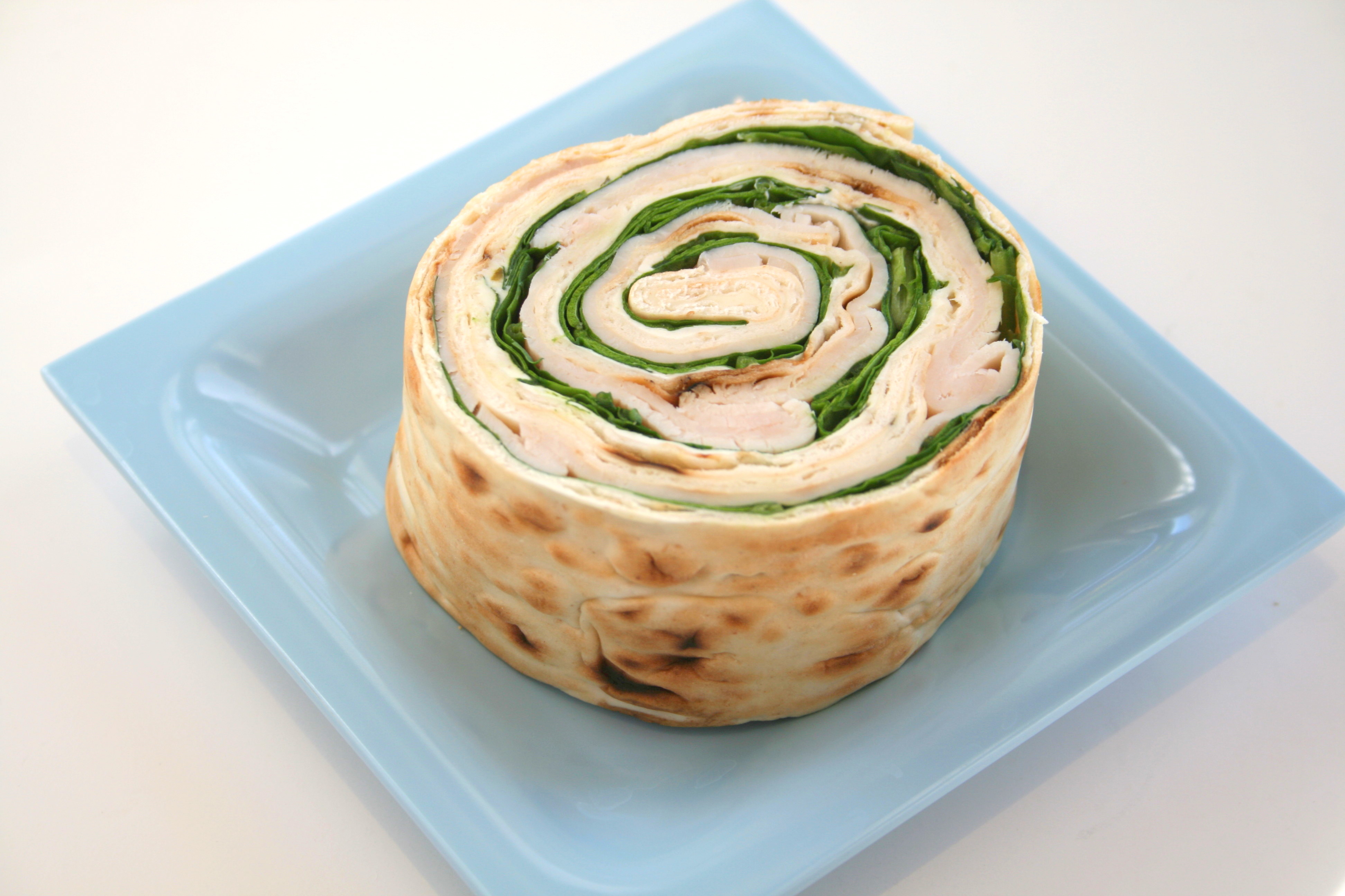 Turkey Pinwheel Sandwich with Spinach and Boursin sandwich on a blue plate