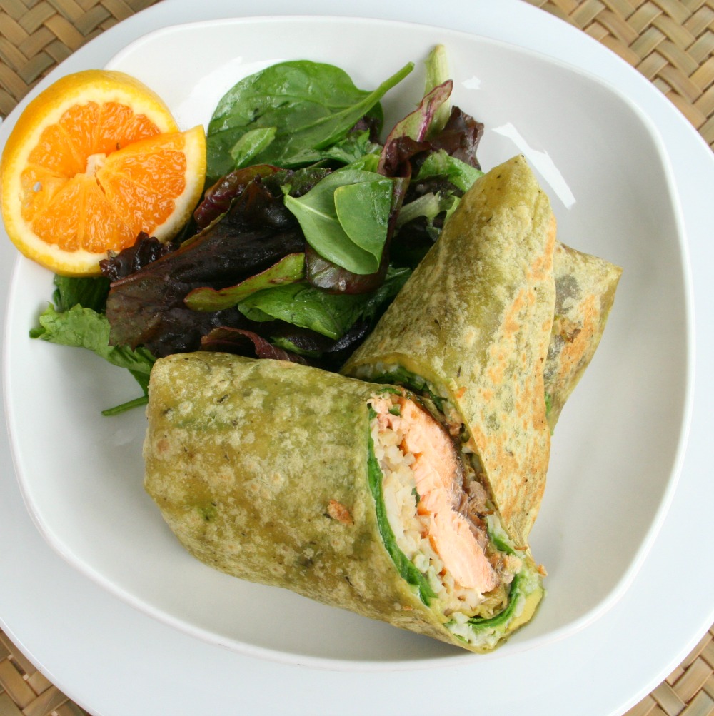 Salmon Wrap Sandwich on a white plate with a salad and orange slices alongside 