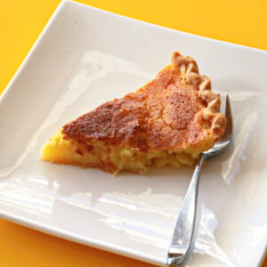 Meyer Lemon Chess Pie slice on a white square plate with a fork along the back crust