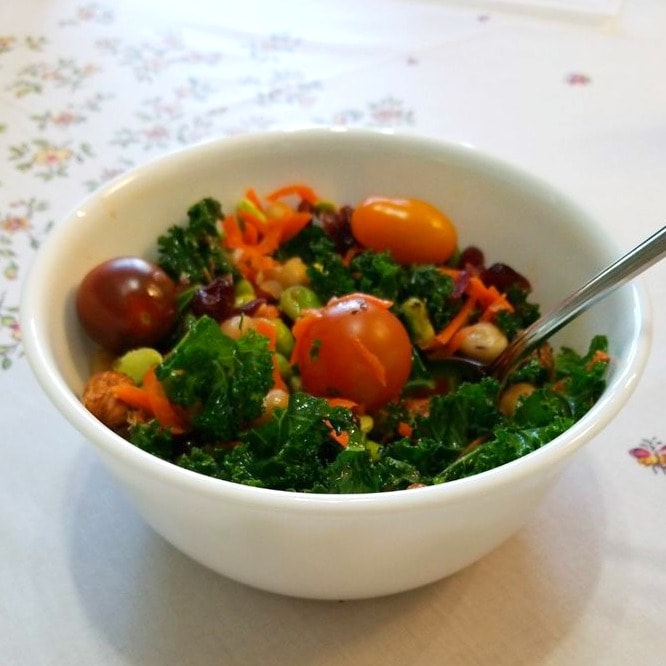 Kale salad with tomatoes on top in a white bowl photo by Katherine Wang