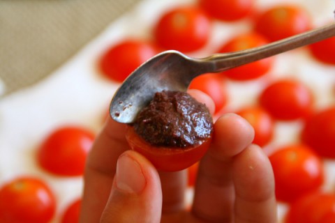 Filling cherry tomatoes with tapenade