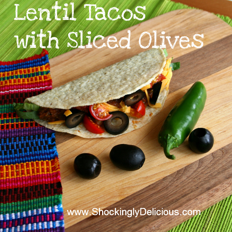 Lentil Tacos with Sliced Olives on a wooden cutting board and a jalapeno on the side