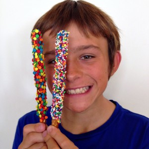 Boy in blue shirt holds 2 pretzel rods and looks out between them