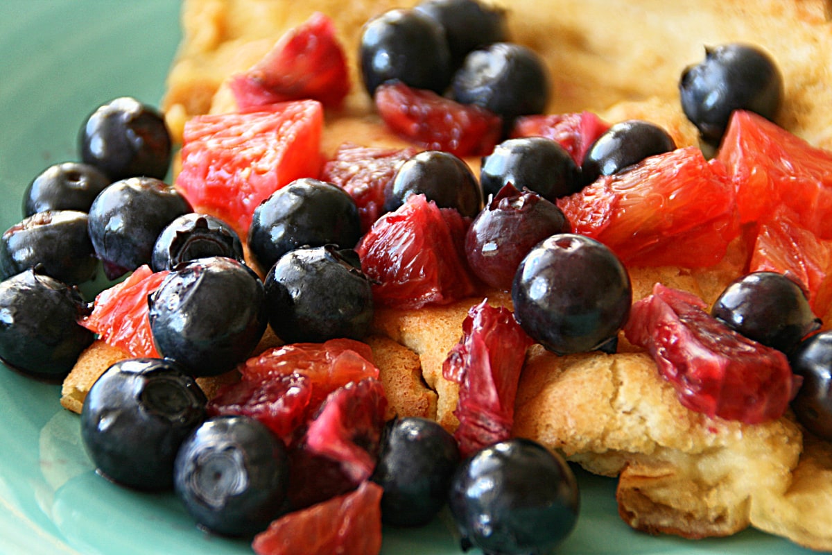 Blueberries and blood oranges piled on a Dutch Baby Pancake