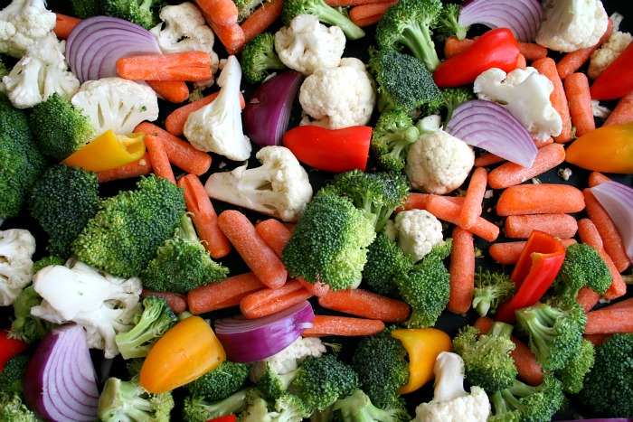 Broccoli, cauliflower, carrots, mini bell peppers and purple onions on a baking sheet on Shockingly Delicious
