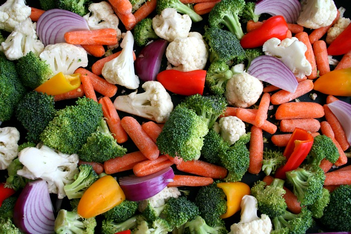 Broccoli, cauliflower, carrots, mini bell peppers and purple onions on a baking sheet on Shockingly Delicious