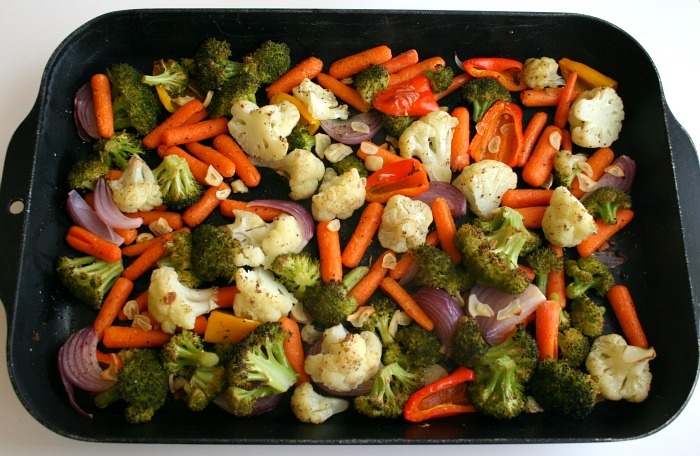 Roasted vegetables in a black baking pan on a white counter on Shockingly Delicious