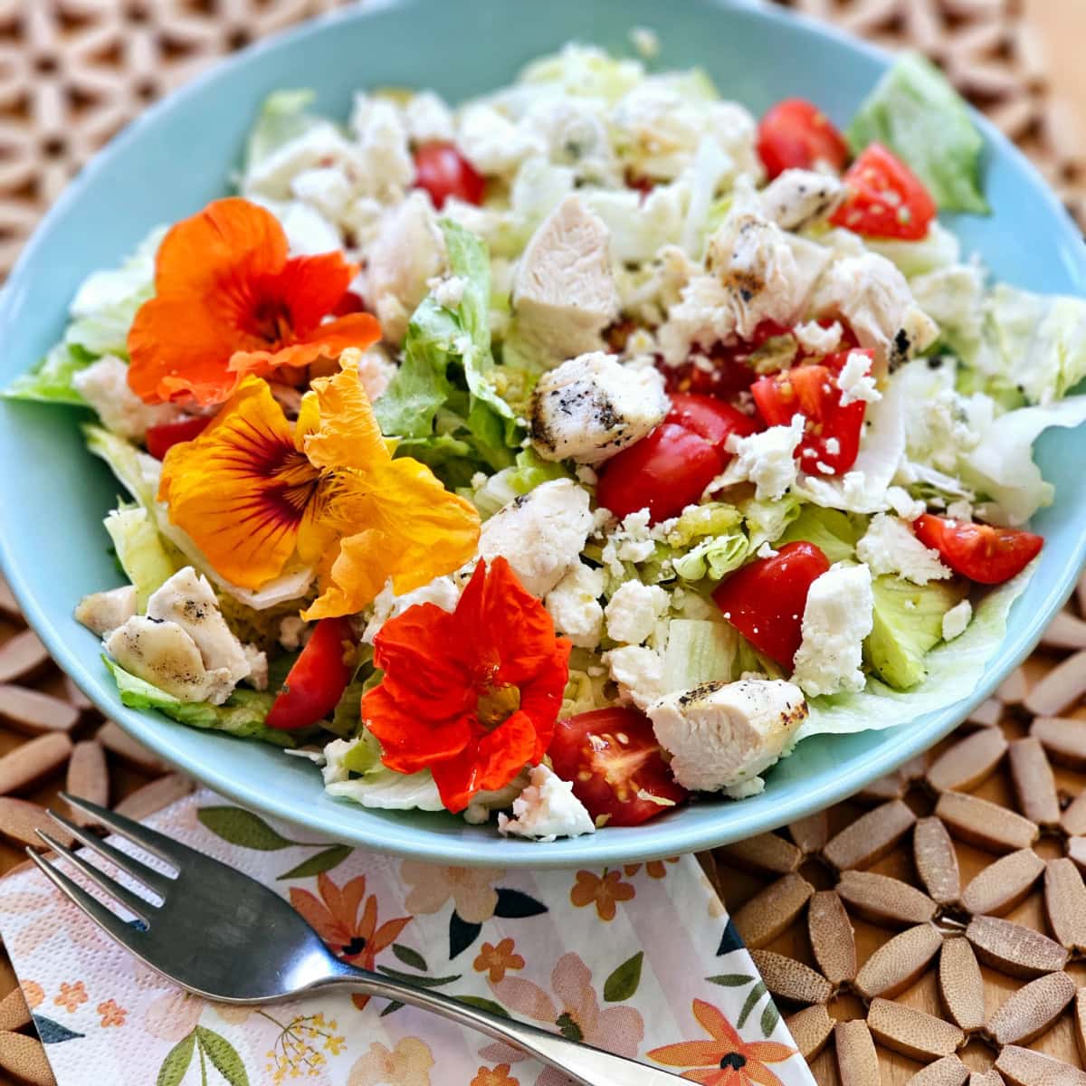 Colorful chopped Wedge Salad in a light blue bowl on a textured wood placemat. 