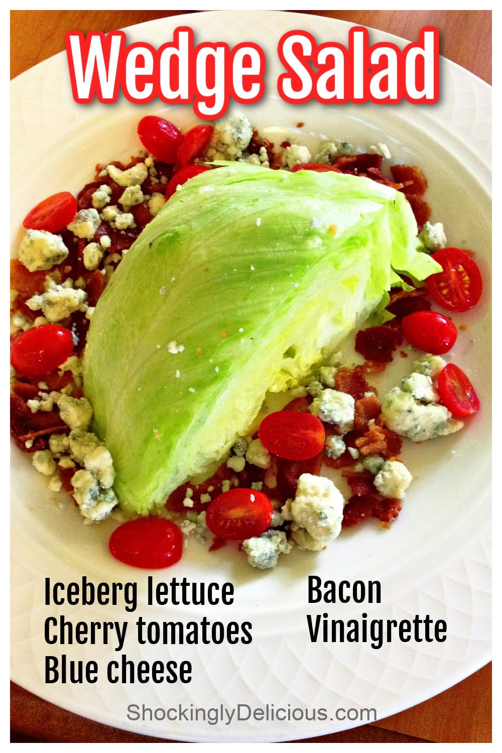 Wedge of green iceberg lettuce on a white plate, surrounded by chopped tomatoes, blue cheese and bacon