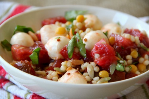 Caprese Grain Salad in a white bowl on a striped tea towel