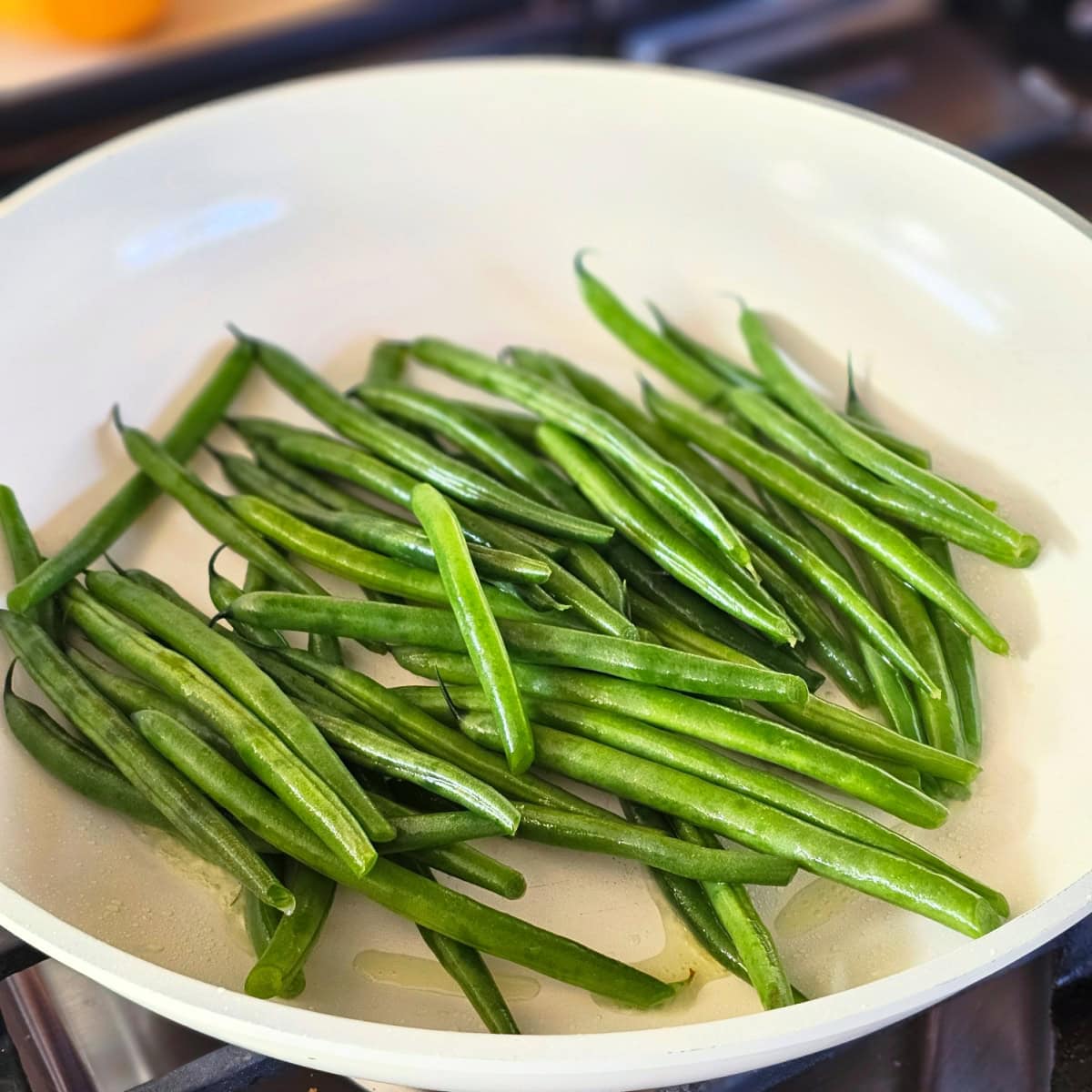 Green beans in a cream-colored skillet with olive oil