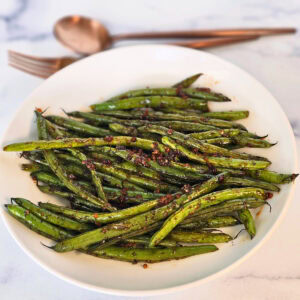 Sweet and Savory Green Beans in a cream colored bowl on a white countertop