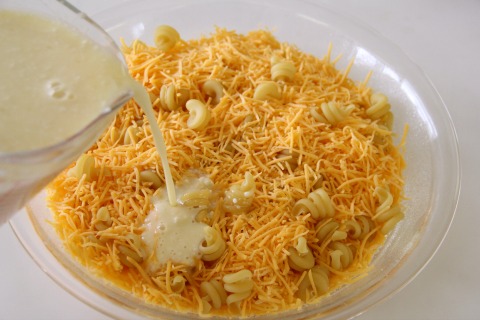 Milk and egg mixture is poured into the pie dish with the cheese and dry macaroni | www.ShockinglyDelicious.com