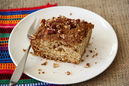 Square piece of Banana Breakfast Cake with Pecan Streusel Topping on a white plate with a fork to the left on www.shockinglydelicious.com