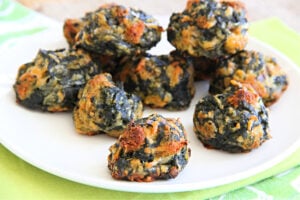 Spinach Balls piled on a white plate sitting on a green napkin