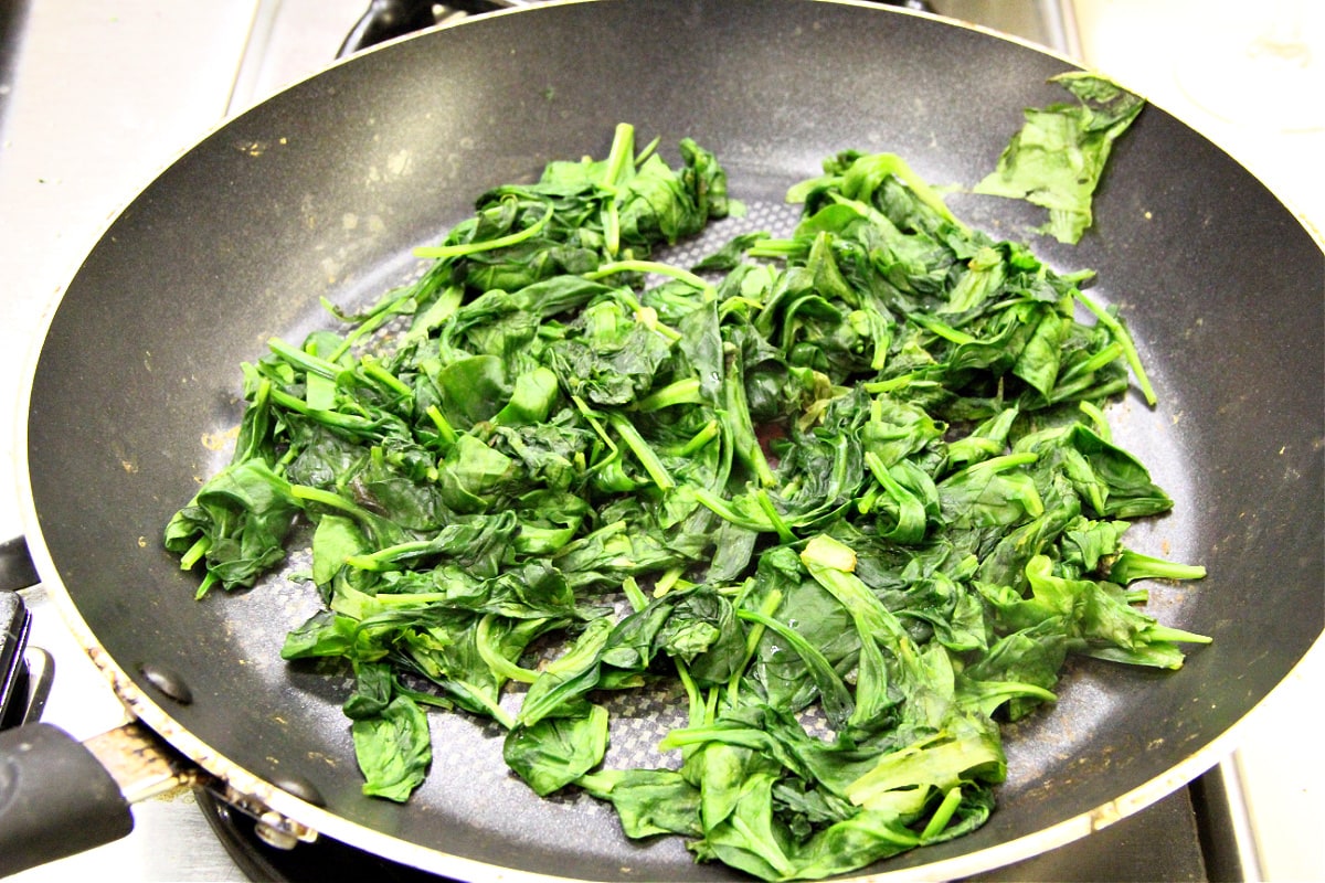 Wilted spinach in a grey skillet