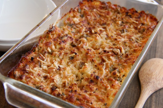 Lower-Fat Cheesy Green Chile Rice in a glass baking dish with a wooden spoon beside it