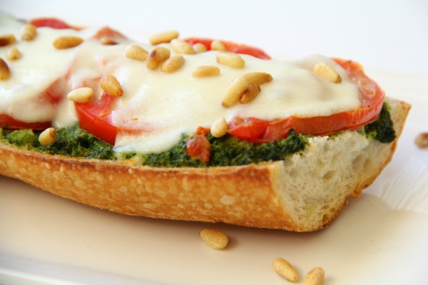 Pesto Caprese French Bread Pizza: A smear of basil pesto, a layering of perfectly fresh, ripe tomatoes, slices of soft fresh mozzarella, a quick pass through the oven, and you have easy pizza perfection. Don't forget to sprinkle the top with toasted pine nuts! #shockinglydelicious #pizzarecipe  #weeknightdinner  #pestopizza #frenchbreadpizza #capresepizza