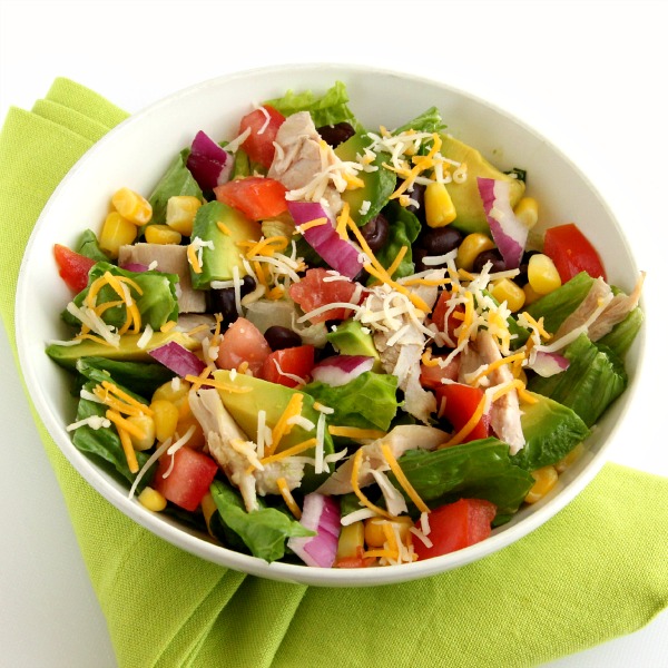 Colorful Chopped Mexican Chicken Salad in a white bowl with a bright green napkin folded underneath