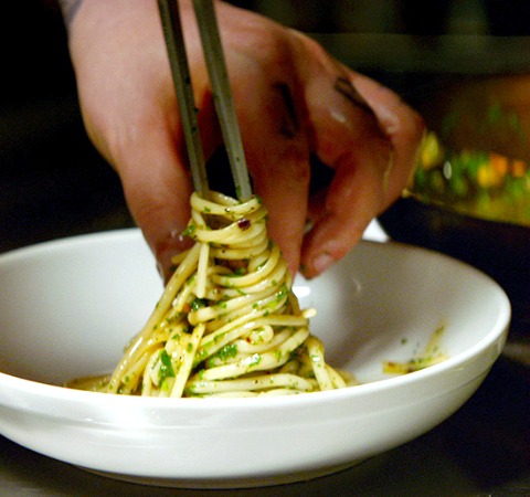 Pasta-Aglio-e-Olio-from-the-movie-chef being twisted around a metal skewer by a hand, in a white bowl