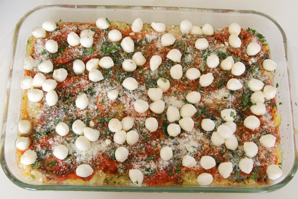 White mozzarella balls dot the top of a tomato sauce covered casserole