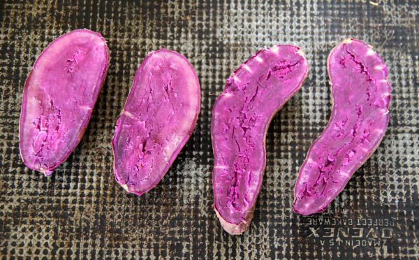 baked Purple Sweet Potato halves on a dark gray baking sheet