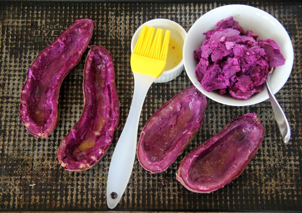 Hollowed out Purple Sweet Potato Skins on a gray baking sheet with a yellow basting brush alongside | Shockingly Delicious