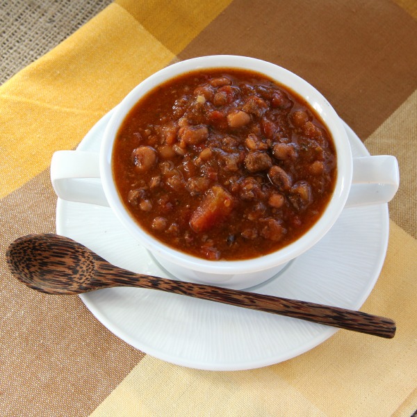 Slow Cooker Black-Eyed Pea Taco Soup in a white bowl on a white plate against a brown and yellow napkin