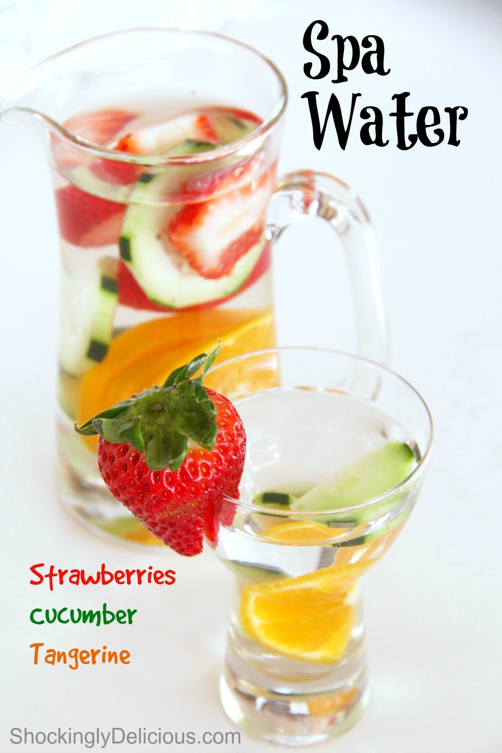 Glass of water with cut fruit in it in front of a pitcher of water with fruit in it