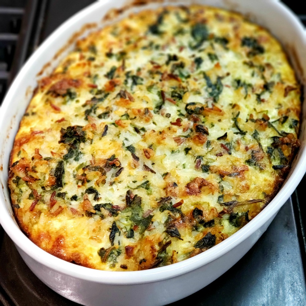 Spinach Rice Cheese Casserole in a white oval dish on a dark surface