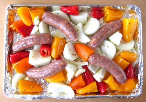 Lay sausages on top of onions, peppers and garlic on ShockinglyDelicious.com