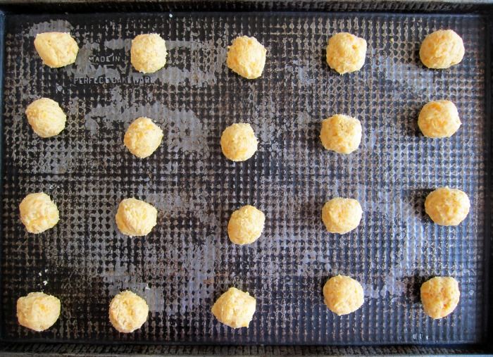 Cheese Crispies rolled into balls and placed on a dark cookie sheet 