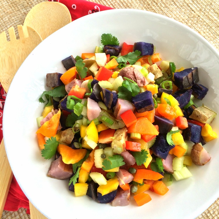 Grilled Rainbow Potato Salad in a white bowl with a bandana for a napkin and burlap for table covering