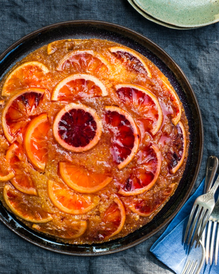 Blood Orange and Olive Oil Polenta Upside-Down Cake on a black cake plate against a dark background