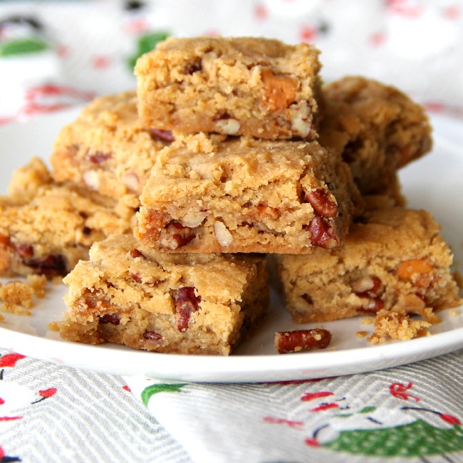 Butterscotch Pecan Shortbread Cookies stacked on a white plate with a Christmas towel underneath