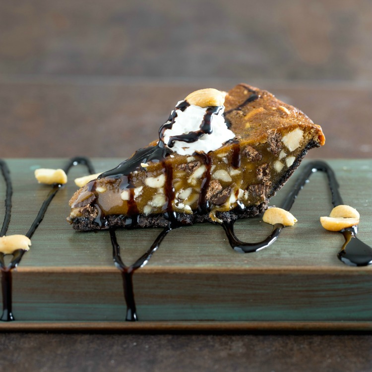 Wedge of Chocolate Chip Peanut Pie with chocolate sauce on top