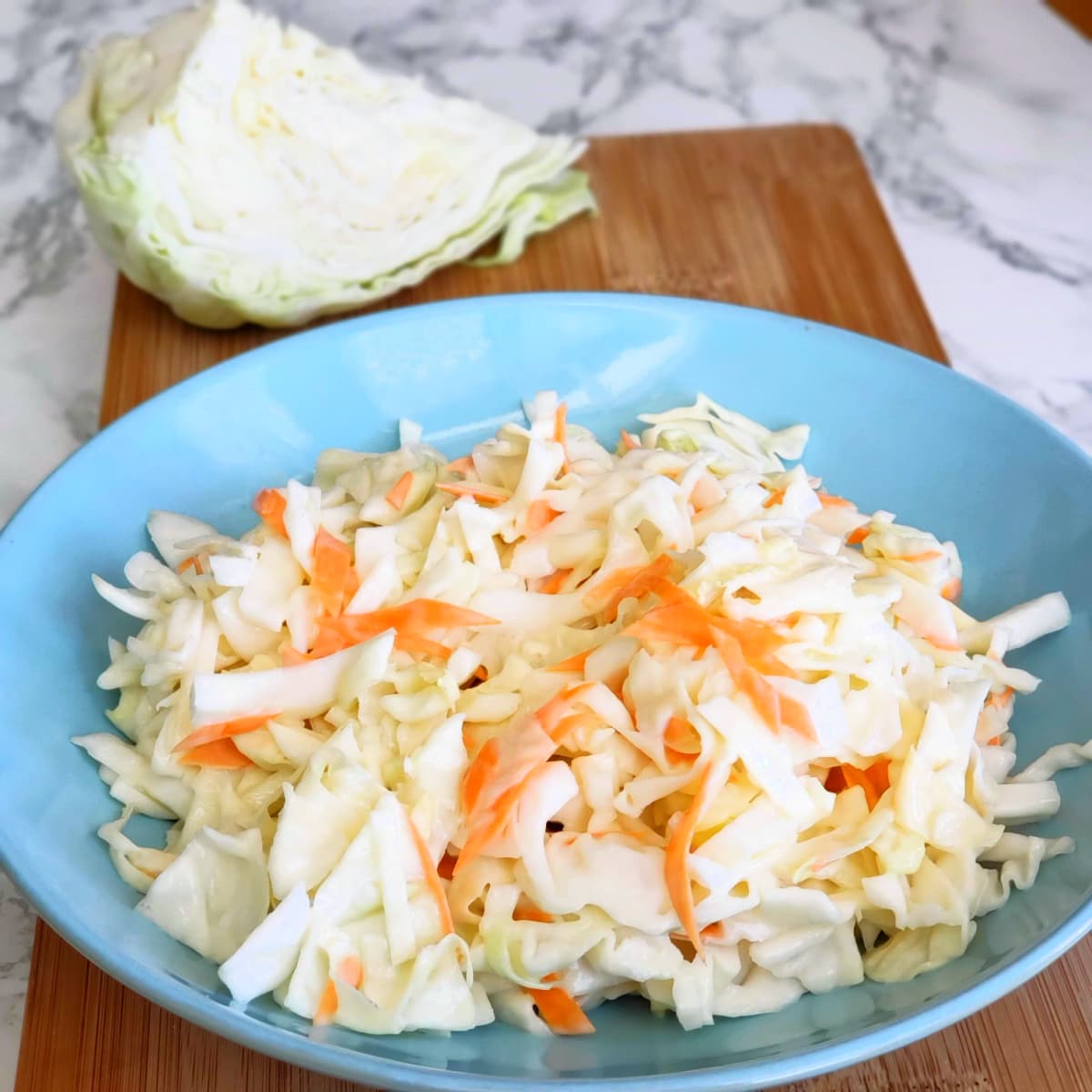Easy Chick-fil-A Cole Slaw in a light blue bowl on a wooden cutting board