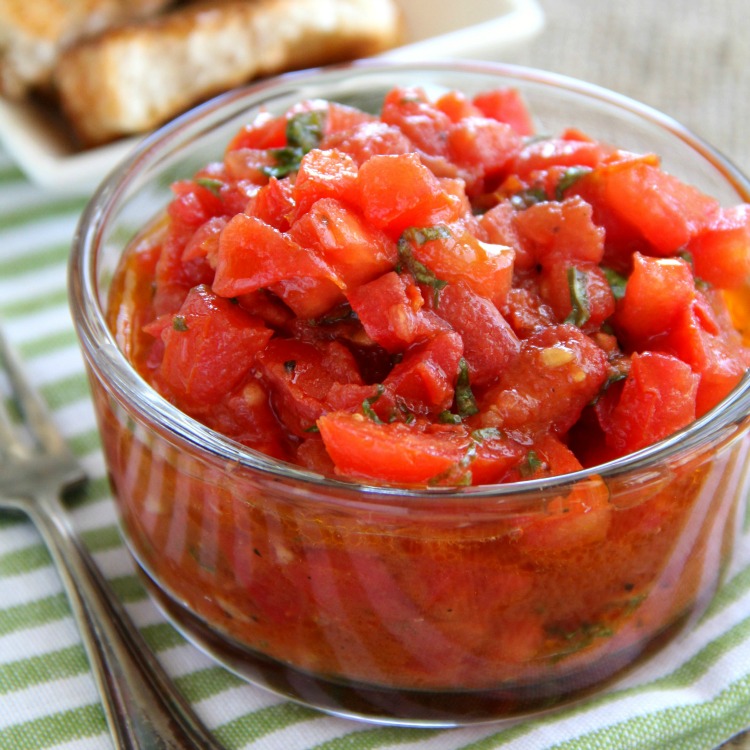 Better Than Trader Joe's Bruschetta Sauce in a glass bowl on a green and white striped towel on ShockinglyDelicious.com