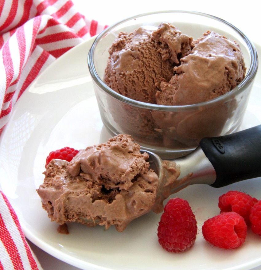 No-Churn Fluffy Milk Chocolate Ice Cream in a glass bowl and an ice cream scoop, with raspberries alongsidecom
