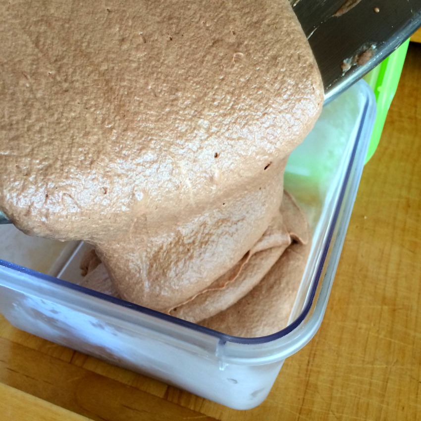 No-Churn Fluffy Milk Chocolate Ice Cream being poured into a plastic container.