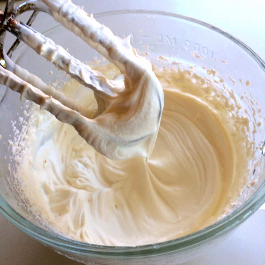Beater lifted out of the bowl shows whipped cream to firm peaks. 